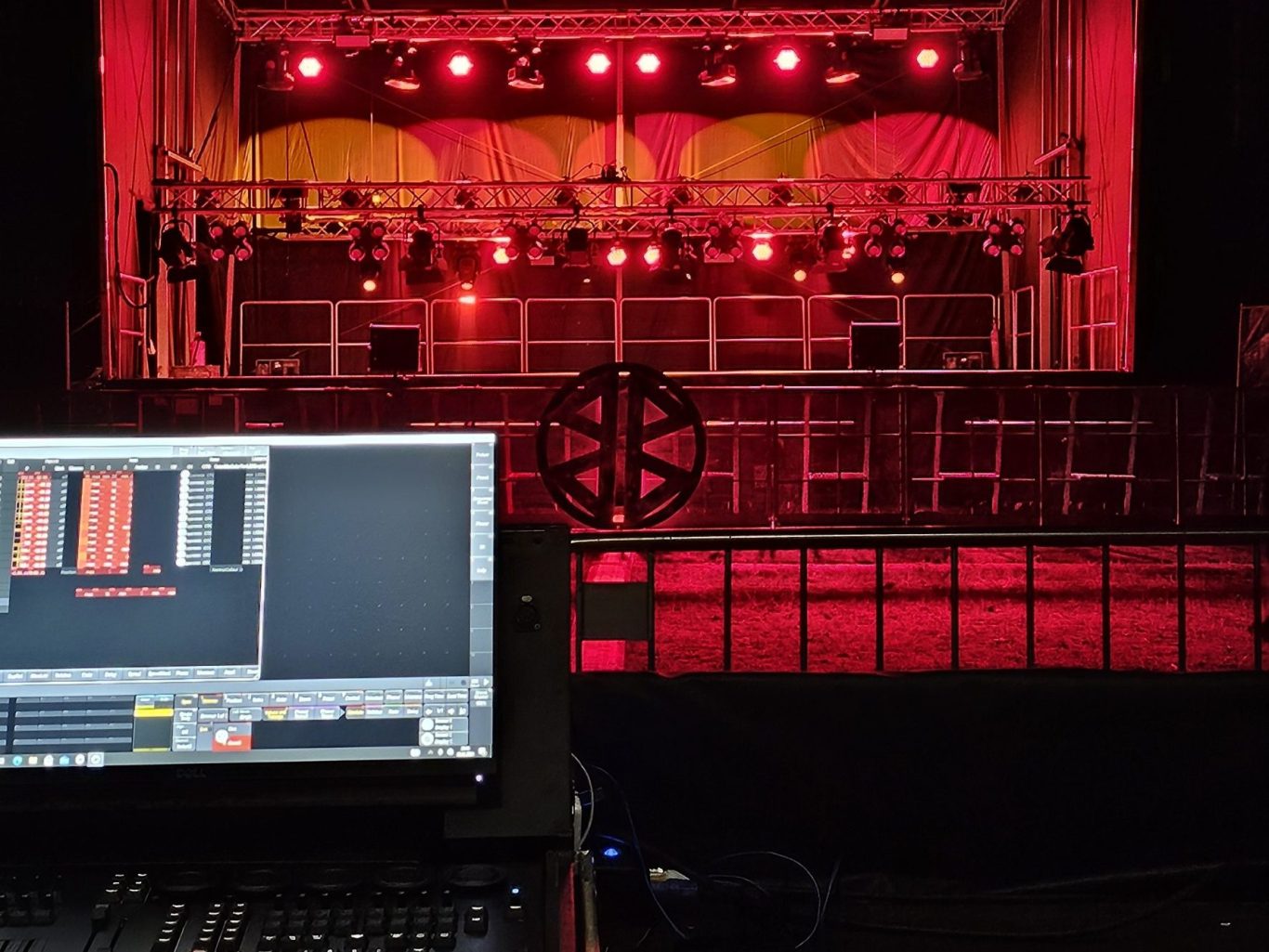 Bühne mit roten/orangem Lichtern im Hintergrund, Sicht von der Technik/FOH.